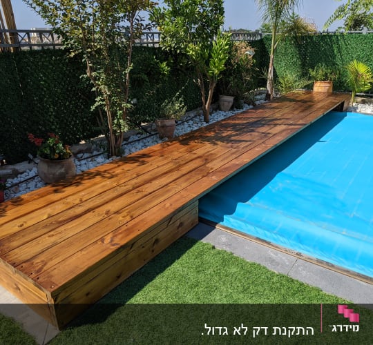 דק עץ ליד בריכה מכוסה ביריעה כחולה